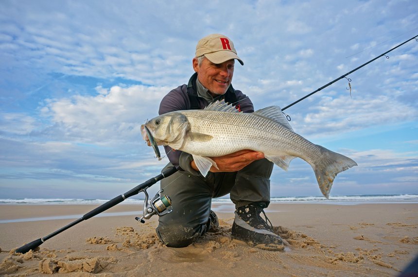 Pêcheur lançant loin du bord de mer avec longue canne