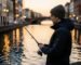 Un jeune pêcheur urbain pratiquant le street fishing sur les quais d'un canal en ville au coucher du soleil